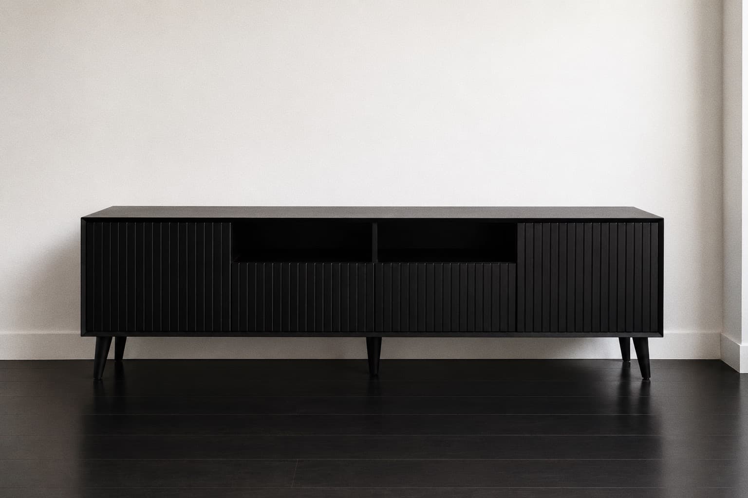 Black fluted NDB media console on tapered legs against a white wall.