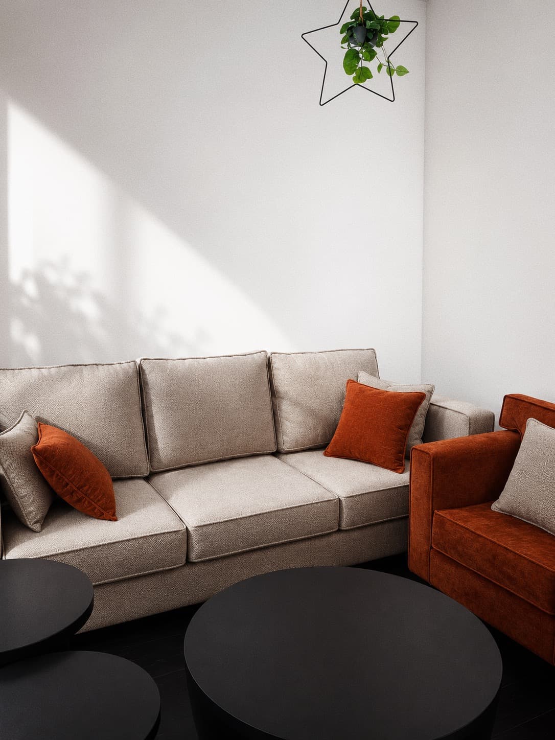 NDB greige sofa with rust cushions beside a rust armchair and black round tables in a sunlit living room.