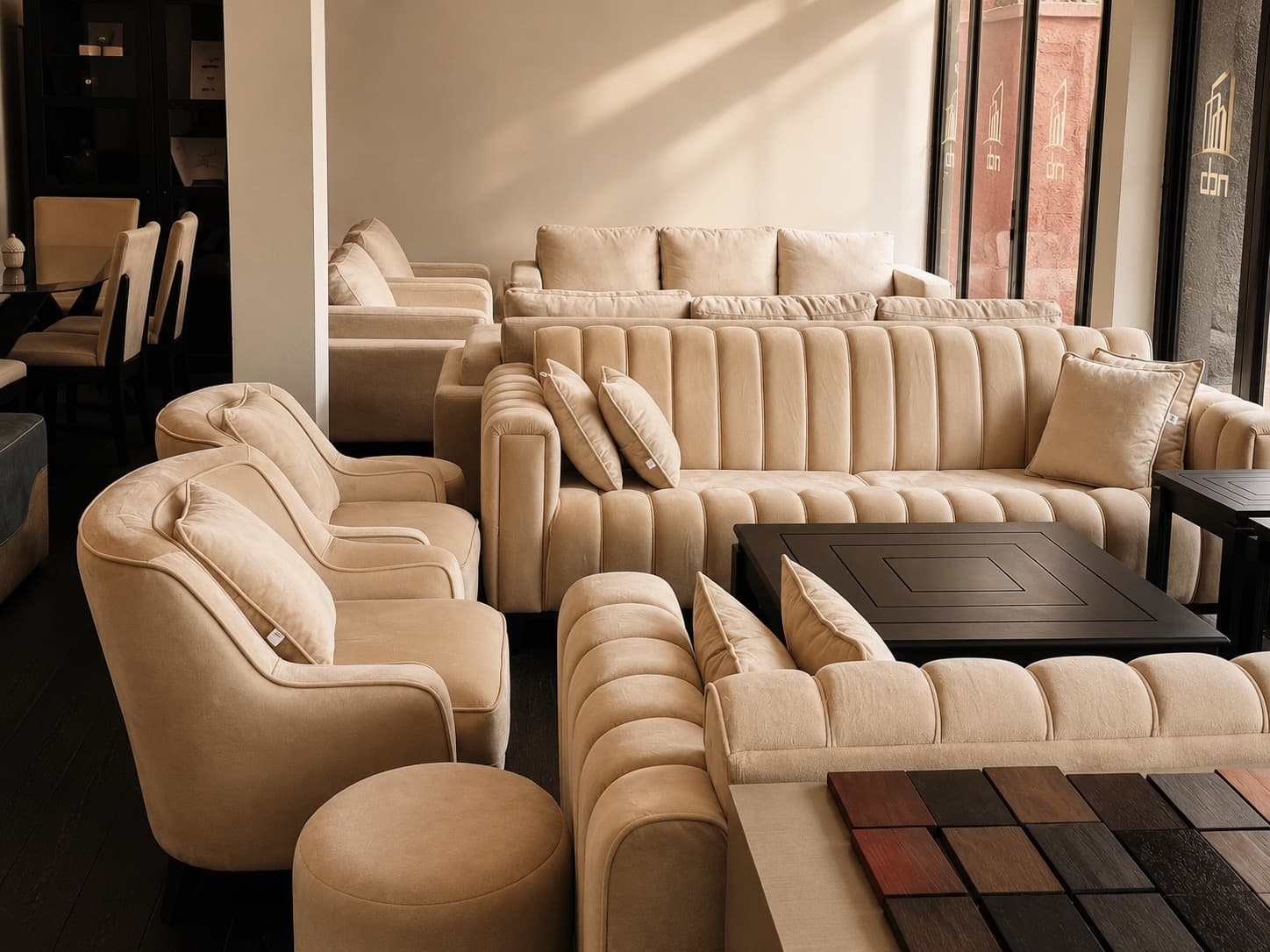 Timber finish samples laid out on a bench in the NDB showroom, beside channel-tufted sofas.