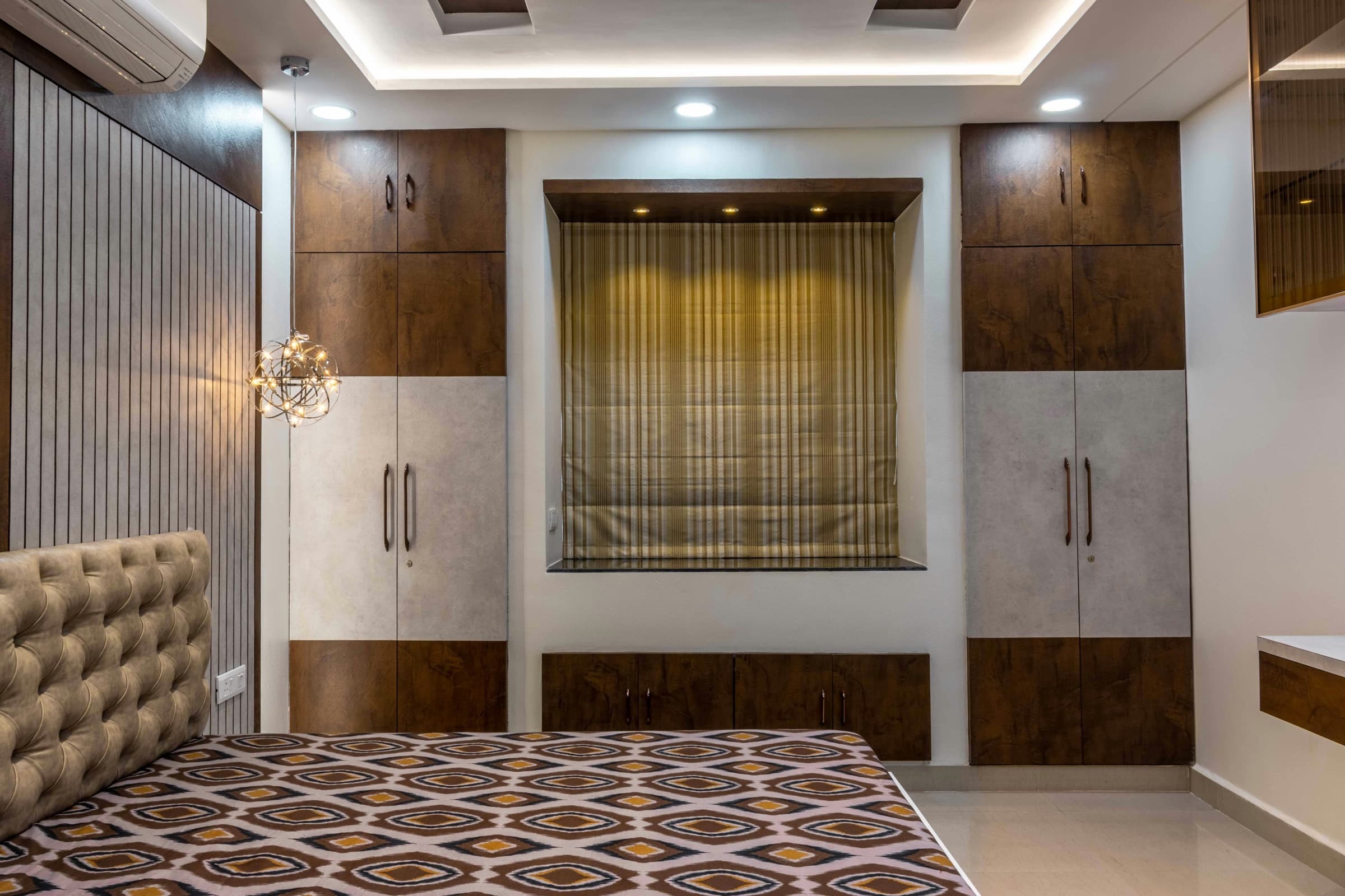 A bedroom wall of floor-to-ceiling fitted wardrobes in two-tone timber and stone finishes.