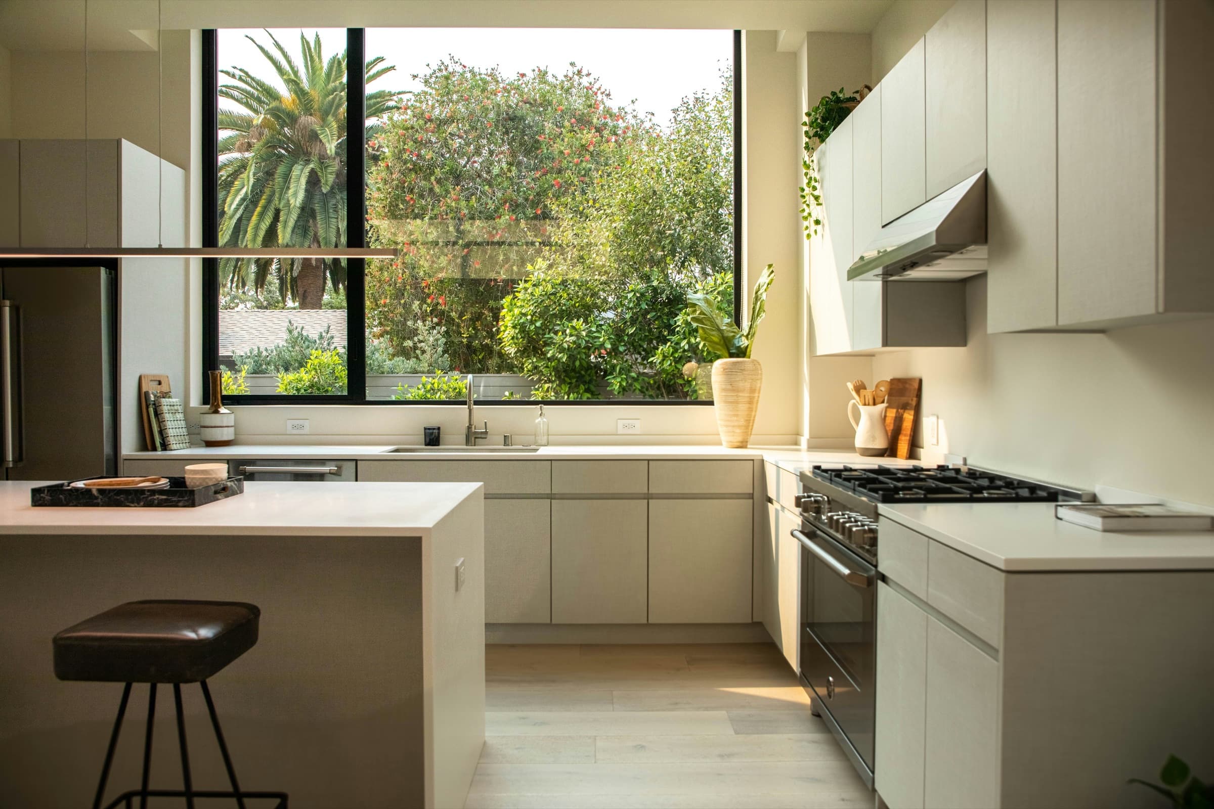 A bright modern kitchen with pale cabinetry, an island and a full-height garden window.